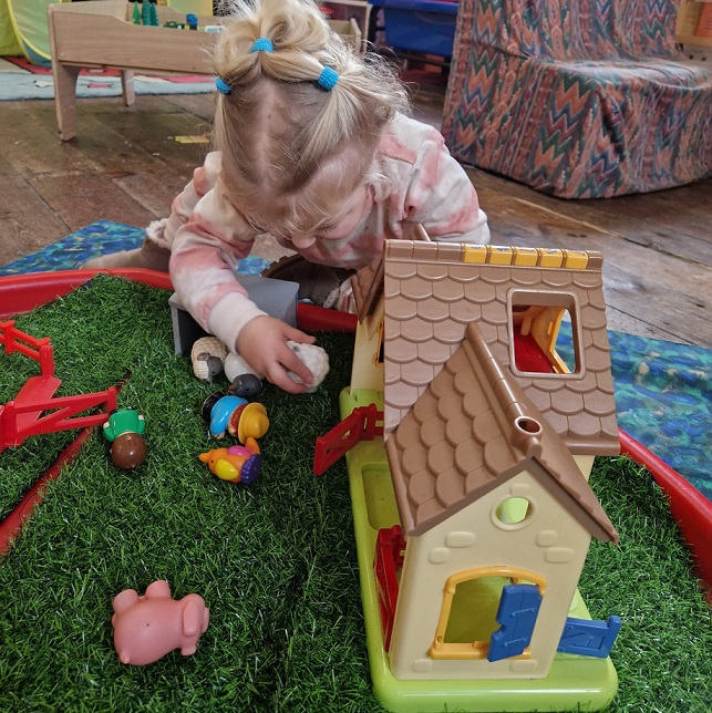 Little girl playing with farmyard toy